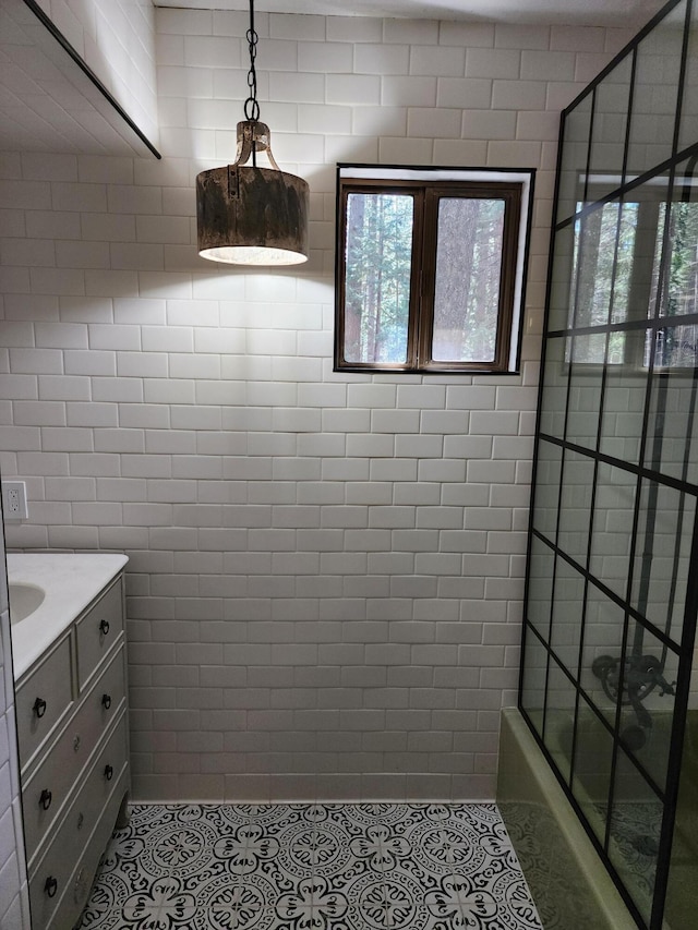 full bath with combined bath / shower with glass door, vanity, and tile patterned floors