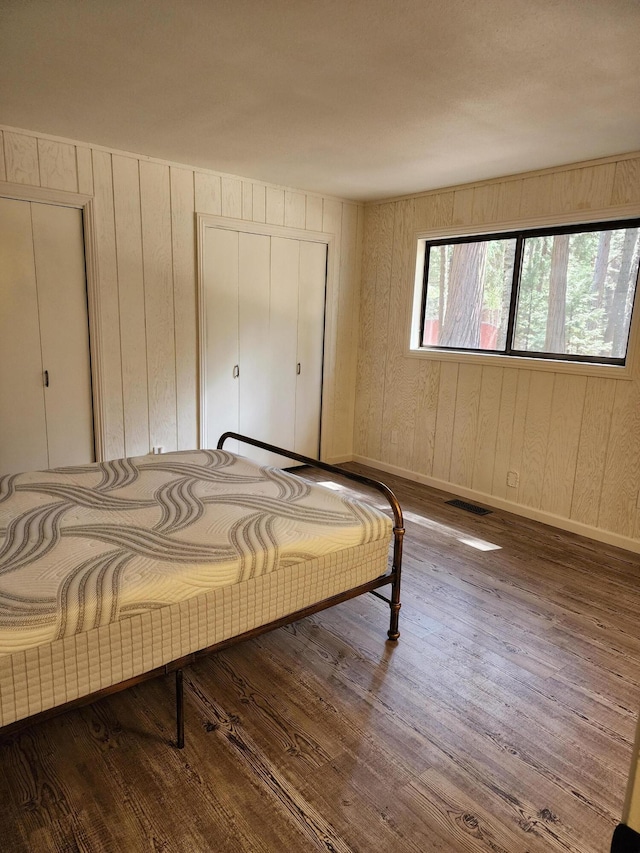 bedroom with baseboards, visible vents, and wood finished floors