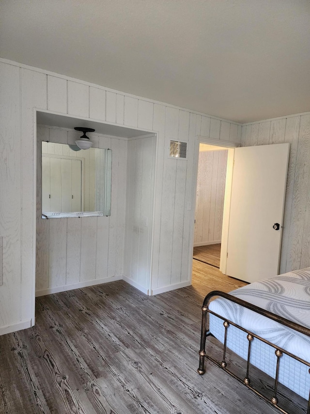 unfurnished bedroom featuring a closet, visible vents, baseboards, and wood finished floors