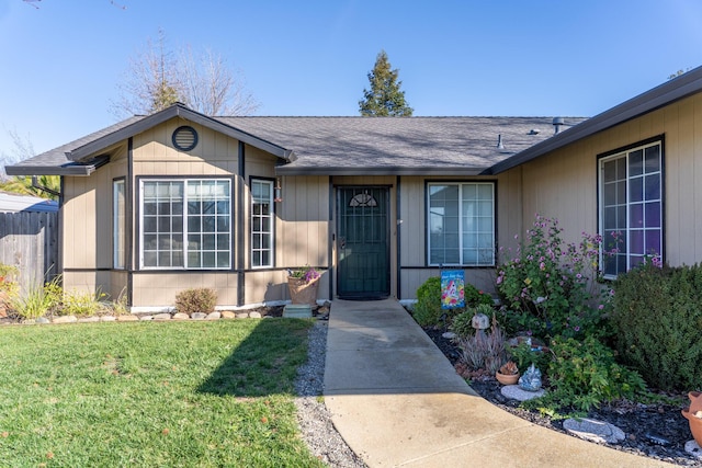 exterior space featuring a shingled roof, a front yard, and fence