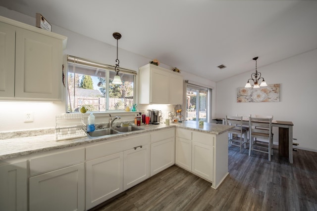 kitchen featuring a sink, dark wood-style floors, white cabinetry, a chandelier, and vaulted ceiling