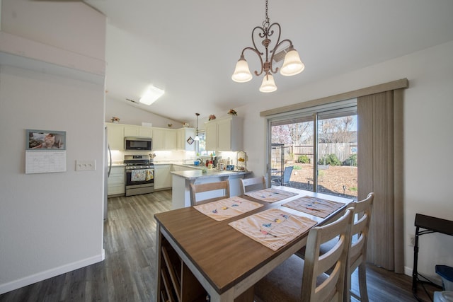 dining space featuring a chandelier, baseboards, lofted ceiling, and wood finished floors