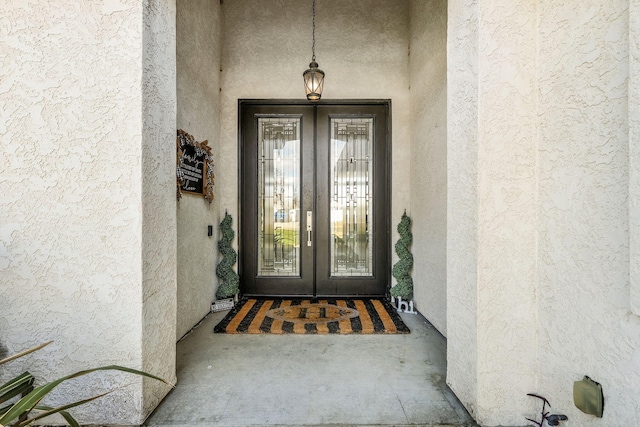 entrance to property featuring french doors and stucco siding