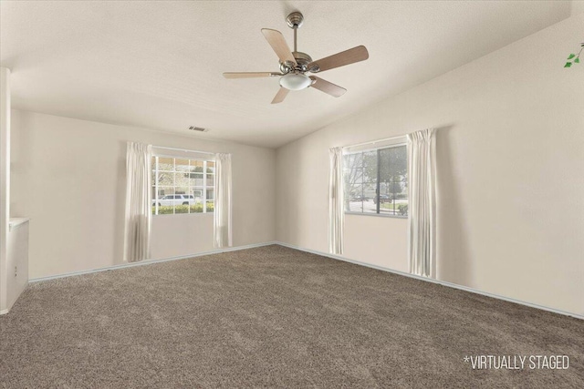 empty room with lofted ceiling, ceiling fan, a textured ceiling, carpet flooring, and visible vents