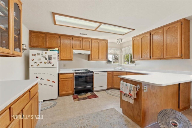 kitchen with under cabinet range hood, a peninsula, white appliances, a sink, and glass insert cabinets