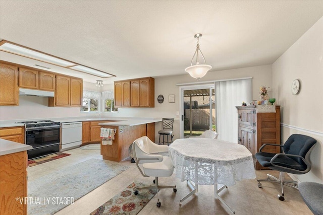 kitchen with under cabinet range hood, white dishwasher, light countertops, and range with gas stovetop