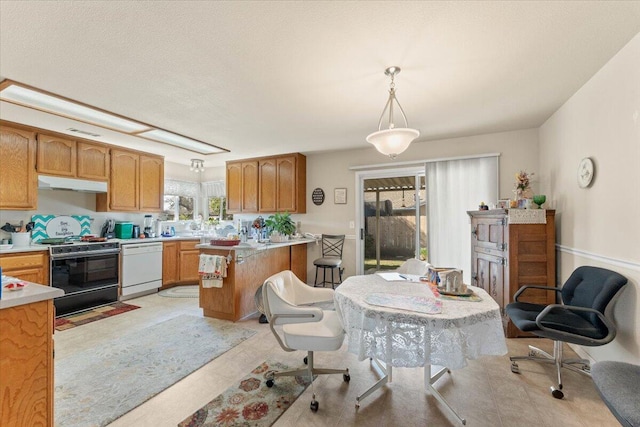 kitchen featuring dishwasher, under cabinet range hood, light countertops, and range with gas stovetop