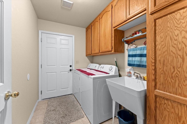 washroom with cabinet space, visible vents, independent washer and dryer, a textured ceiling, and a sink