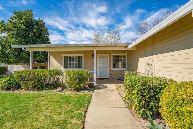 doorway to property with a porch and a lawn