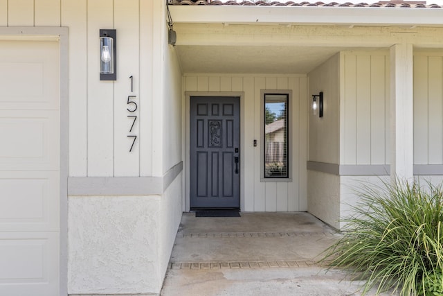 view of exterior entry with a garage and a tiled roof