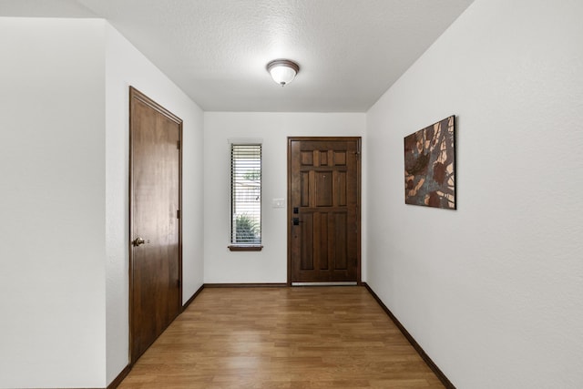 entrance foyer with baseboards, light wood-style flooring, and a textured ceiling