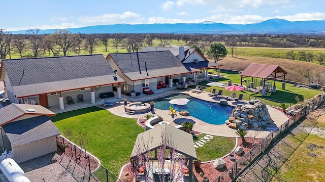 view of swimming pool with a yard, a fire pit, a mountain view, and a patio