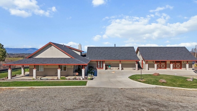 view of front of property with roof with shingles, concrete driveway, and a front yard