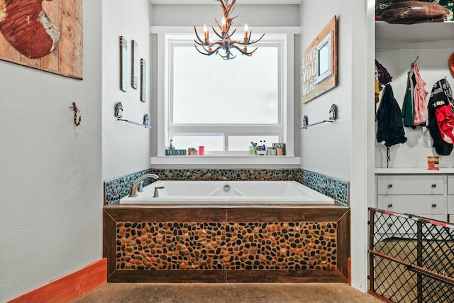 bathroom with a garden tub, an inviting chandelier, and a textured wall