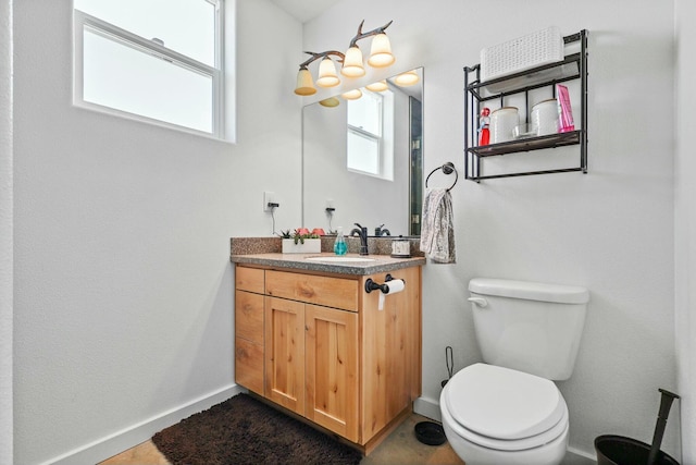 half bathroom featuring toilet, baseboards, and vanity