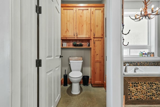 bathroom featuring concrete flooring, a garden tub, toilet, and a notable chandelier