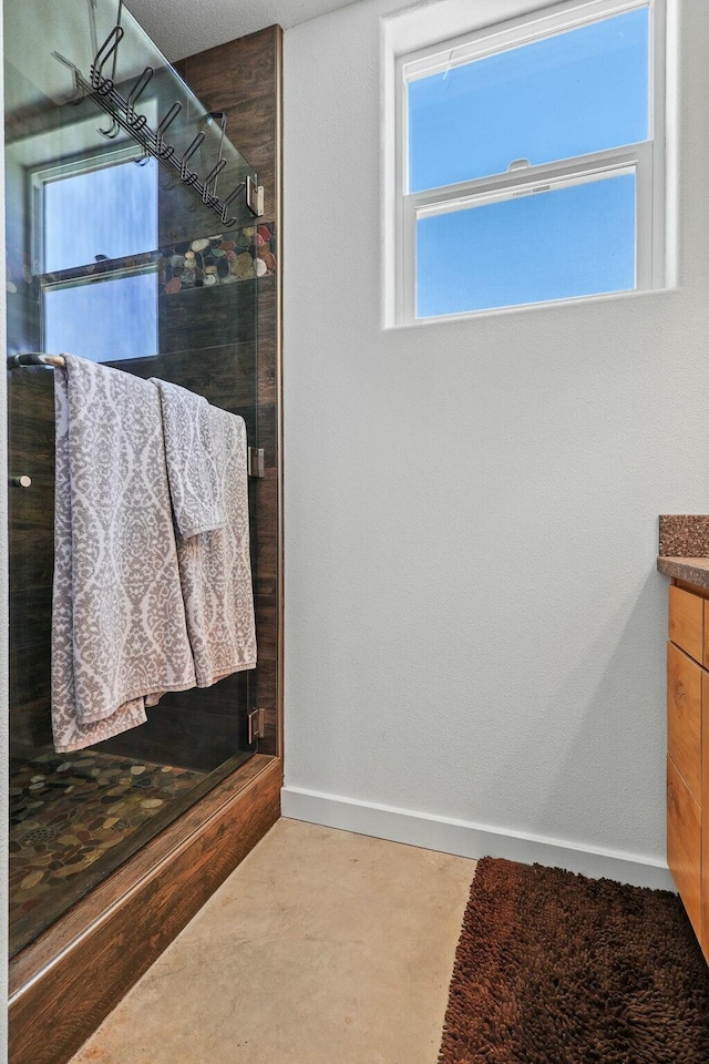 full bath featuring concrete flooring, baseboards, a shower stall, and vanity