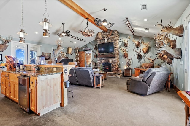 kitchen with lofted ceiling with beams, a fireplace, a sink, visible vents, and open floor plan