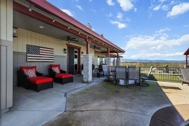 view of patio featuring a mountain view, outdoor dining space, fence, and a ceiling fan