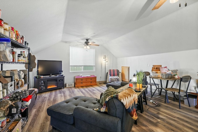 living room with a ceiling fan, vaulted ceiling, and wood finished floors