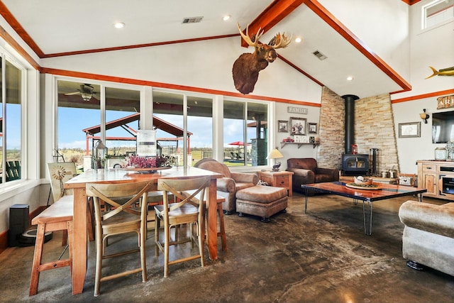 living area with a wood stove, high vaulted ceiling, and visible vents