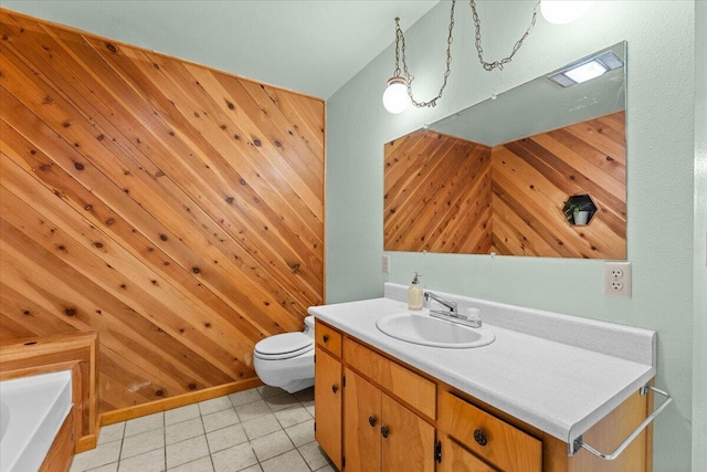 bathroom with toilet, tile patterned flooring, wooden walls, and vanity