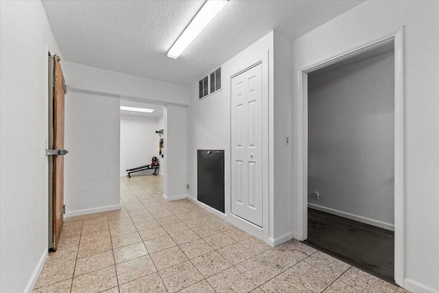 empty room featuring baseboards, visible vents, and a textured ceiling