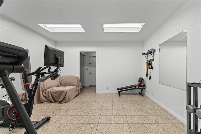 exercise room featuring baseboards and light floors