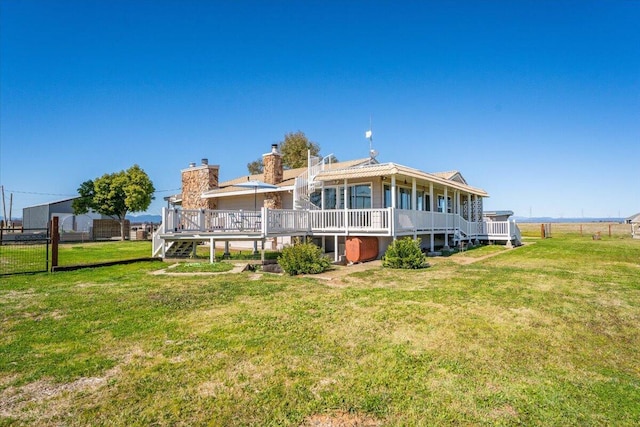 rear view of property featuring a deck, a yard, a chimney, and fence