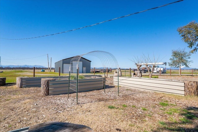 view of home's community featuring a vegetable garden, a detached garage, a pole building, and an outdoor structure