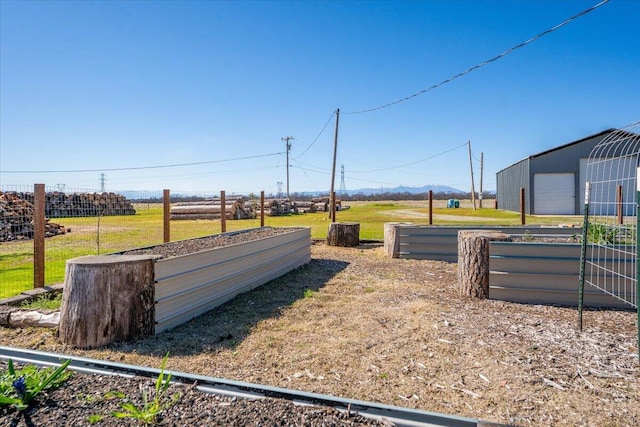 view of yard featuring a garage, a garden, and an outdoor structure