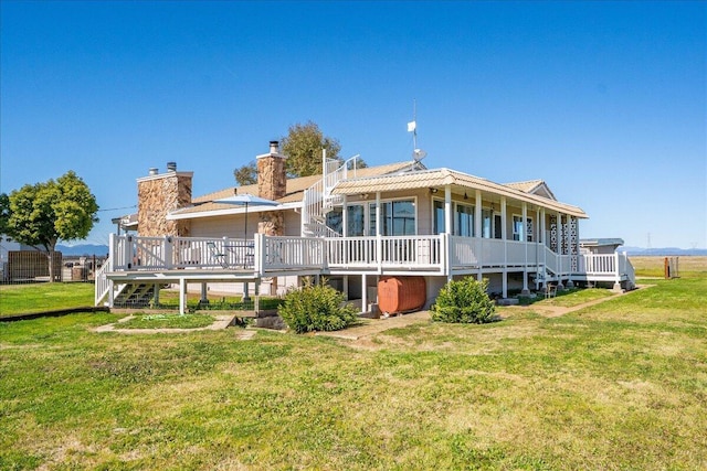 rear view of property with a deck, a yard, and a chimney