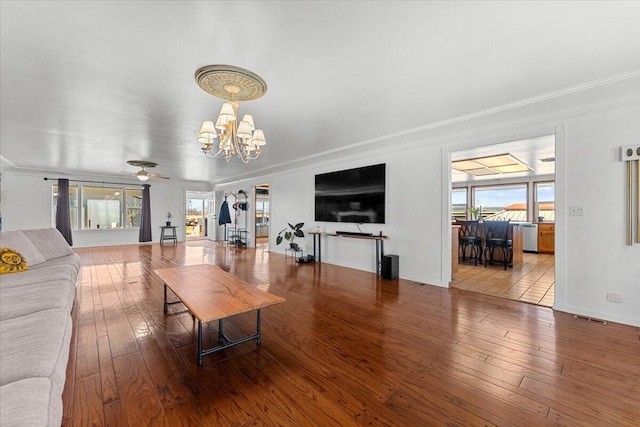 living area featuring a chandelier, visible vents, hardwood / wood-style flooring, and crown molding