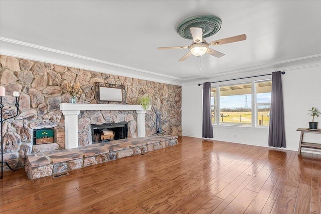 living area featuring visible vents, hardwood / wood-style flooring, ceiling fan, ornamental molding, and a fireplace