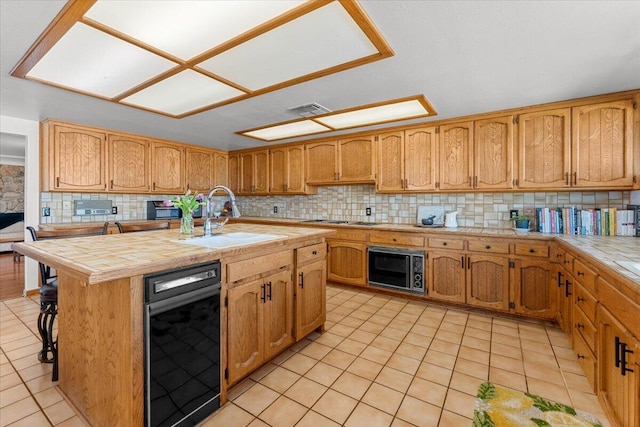 kitchen featuring tile countertops, light tile patterned floors, a sink, visible vents, and decorative backsplash