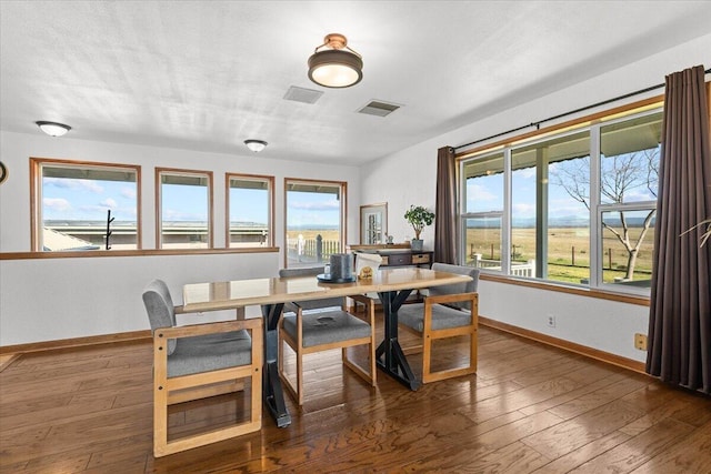 dining space featuring a textured ceiling, hardwood / wood-style flooring, visible vents, and baseboards