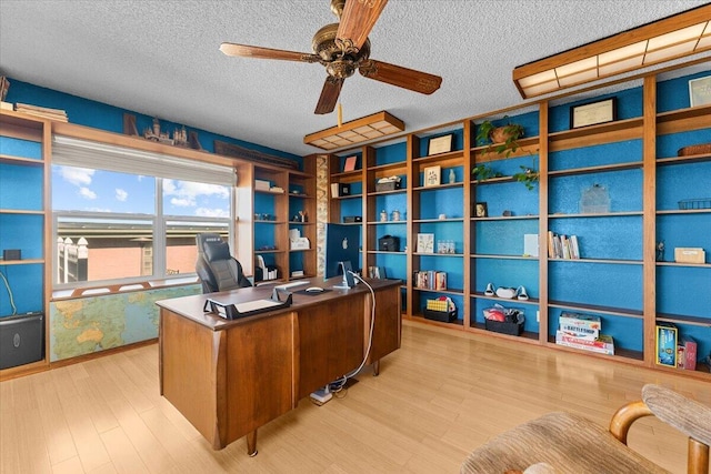 office area with a textured ceiling, ceiling fan, and light wood-style floors