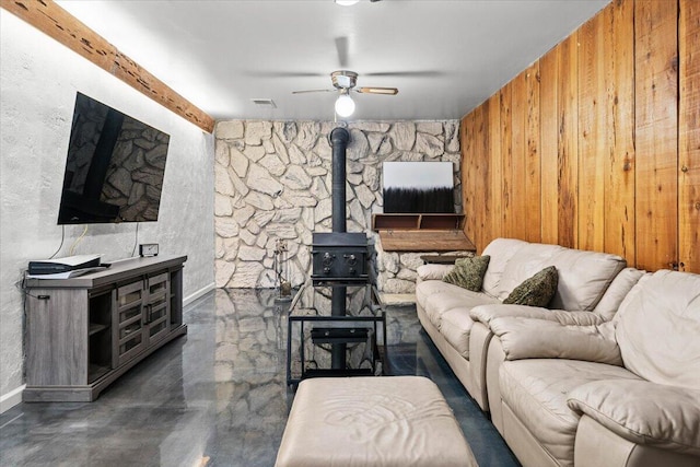 living area featuring visible vents, concrete floors, a wood stove, and a ceiling fan