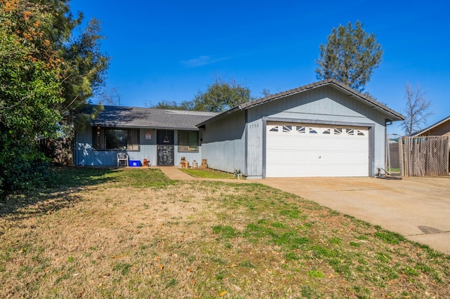 single story home featuring a front yard, driveway, an attached garage, and fence