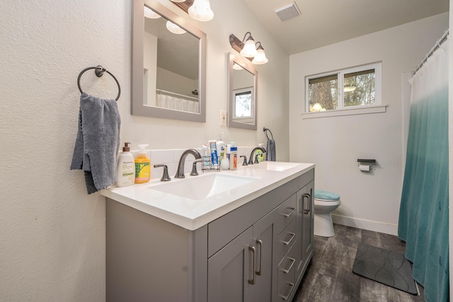 bathroom with visible vents, a sink, toilet, and double vanity