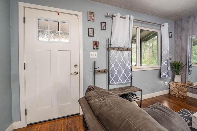 interior space with a textured ceiling, baseboards, and wood finished floors