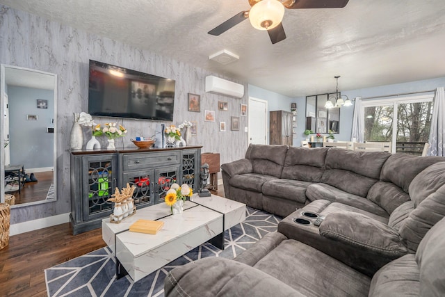 living room featuring dark wood-style floors, an AC wall unit, a textured ceiling, baseboards, and ceiling fan with notable chandelier