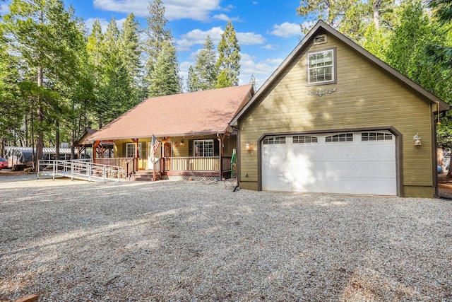 chalet / cabin featuring a porch and gravel driveway