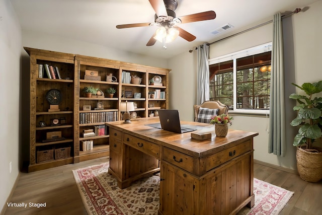 office space featuring a ceiling fan, visible vents, and wood finished floors