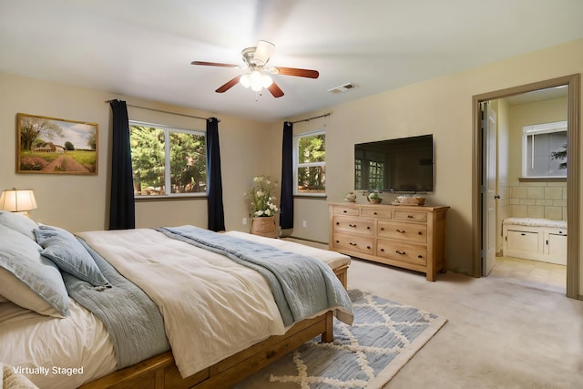 bedroom featuring visible vents, ensuite bathroom, and light colored carpet