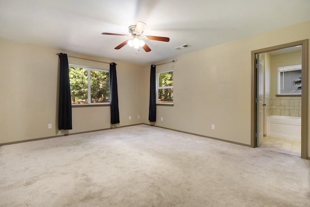 spare room with light carpet, baseboards, visible vents, and ceiling fan