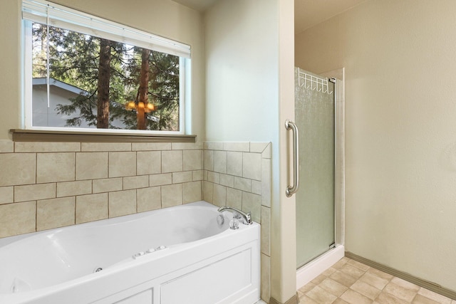 bathroom with a stall shower, a bath, and baseboards