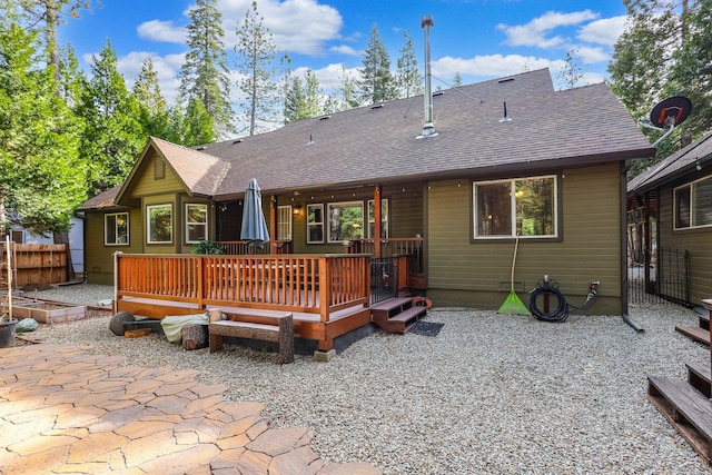 rear view of property featuring a vegetable garden, roof with shingles, fence, and a deck