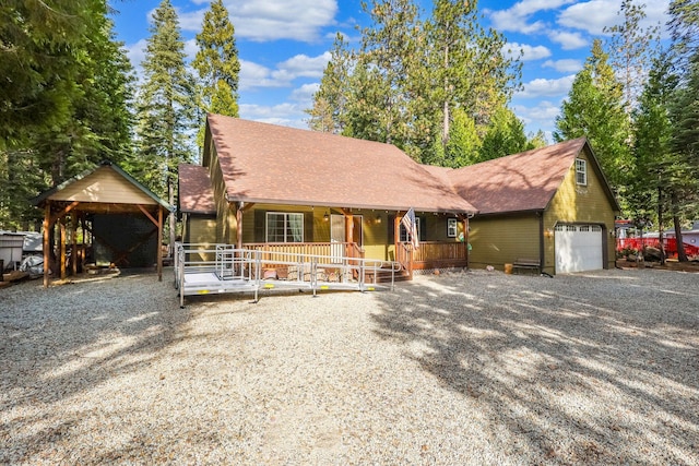 chalet / cabin featuring an attached garage, covered porch, gravel driveway, and roof with shingles