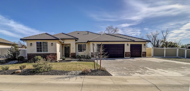 view of front of house featuring a garage, stone siding, fence, and concrete driveway